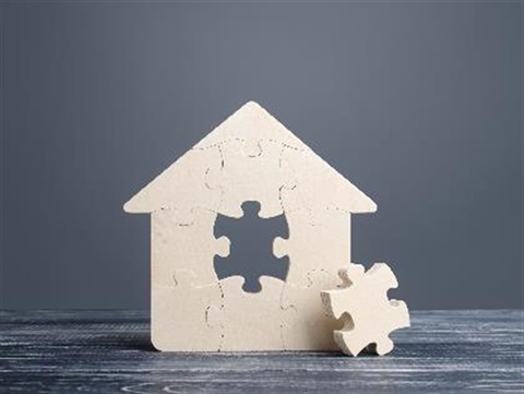House made of puzzle pieces with one piece out of place. 