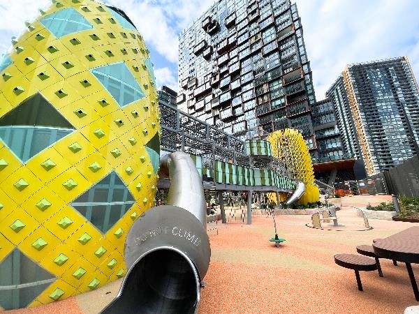 Two yellow playground towers with apartment block in the background