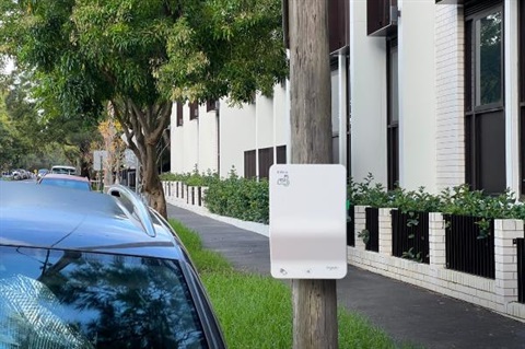 A car parked next to a power pole with an EV charger attached to it