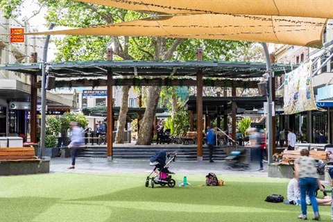 Lane Cove Plaza Green. People are walking, sitting and eating.