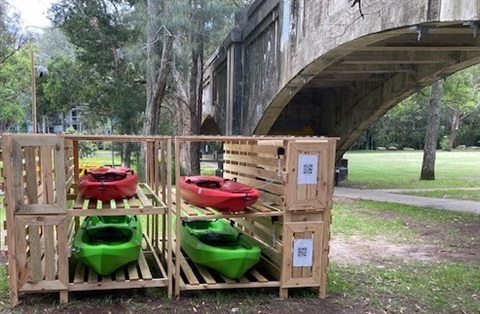 Kayak storage with two red kayaks and two green kayaks at Burns Bay Reserve